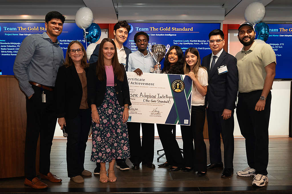 Diverse group of people holding up a large novelty award certificate