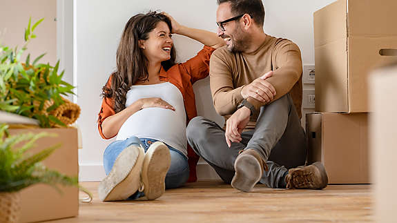 A couple smiling together while sitting on the floor.