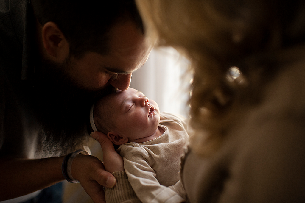 Parents kissing new-born baby