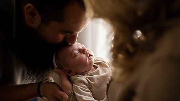 Parents kissing new-born baby