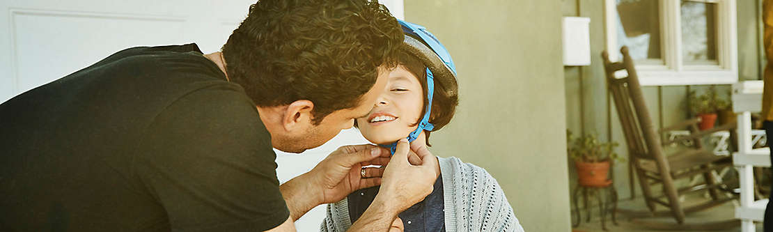 Father getting son ready to ride bike