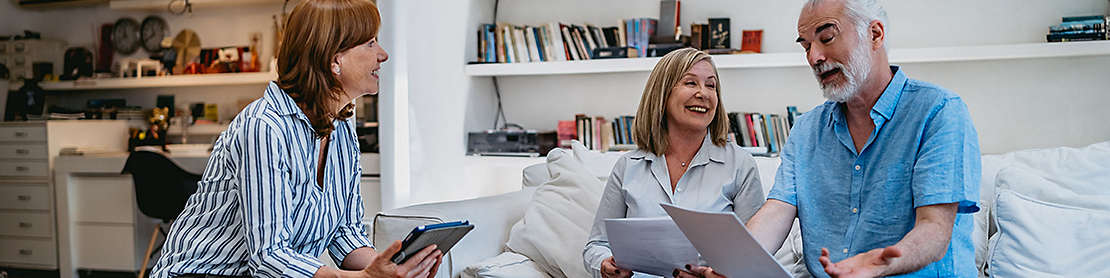 A mature couple at home discussing paperwork with an agent.
