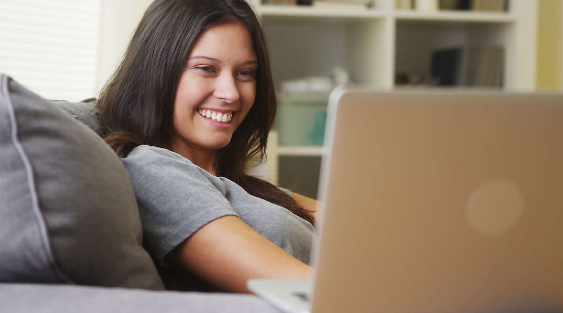 A woman sitting and smiling at her computer.