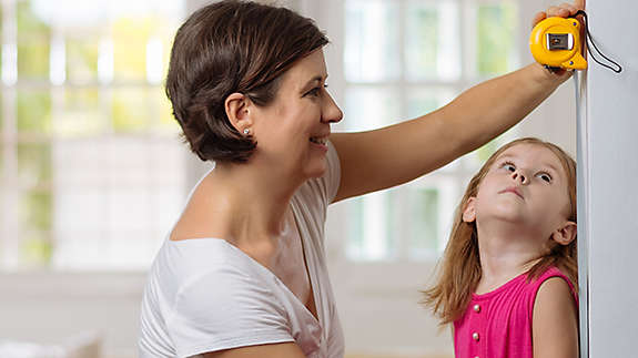 Mother taking height of her daughter