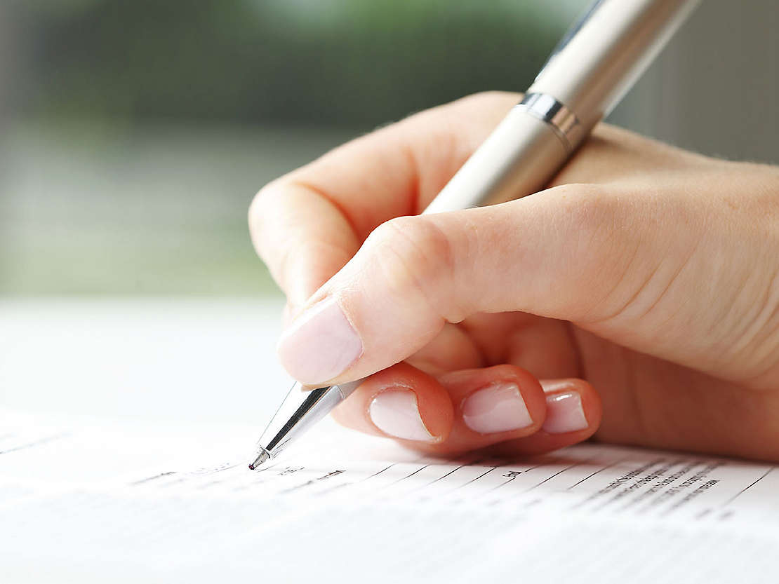 Close up of someone signing paperwork