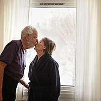 Senior couple kissing next to window 
