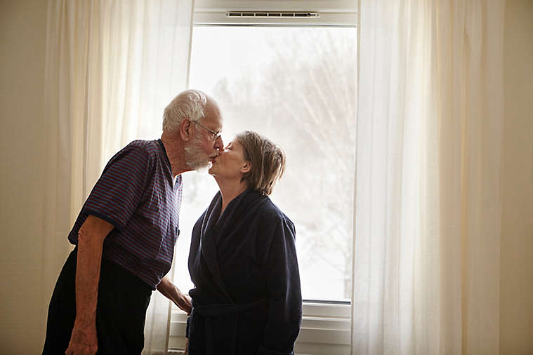 Senior couple kissing next to window 
