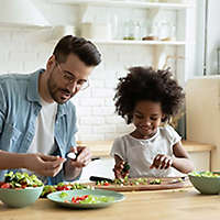 Father and daughter making salad in their kitchen