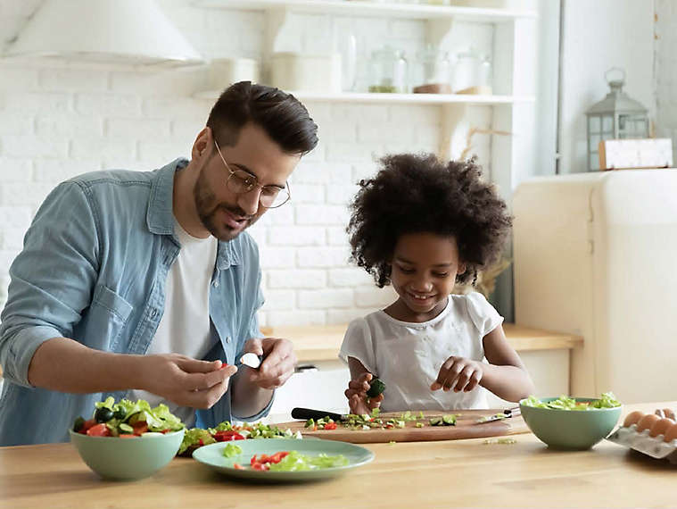 Father and daughter making salad in their kitchen