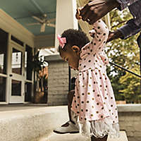 Father and daughter (18 months) walking up steps to house