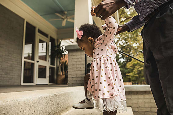 Father and daughter (18 months) walking up steps to house 