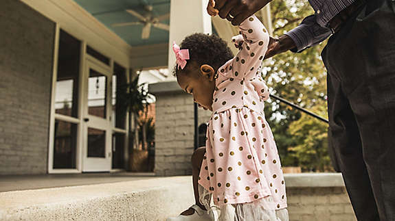 Father and daughter (18 months) walking up steps to house