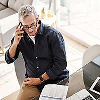 older man on phone looking at papers