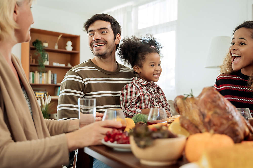 A family sitting around the dinner table laughing.