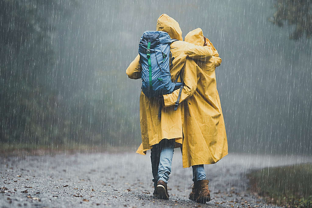 A couple wearing yellow raincoats walking in the rain.