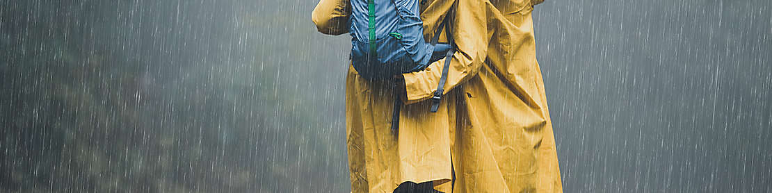 A couple wearing yellow raincoats walking in the rain.