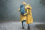 A couple wearing yellow raincoats walking in the rain.