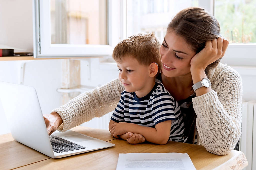 A mother and son sitting at the kitchen table working on a computer