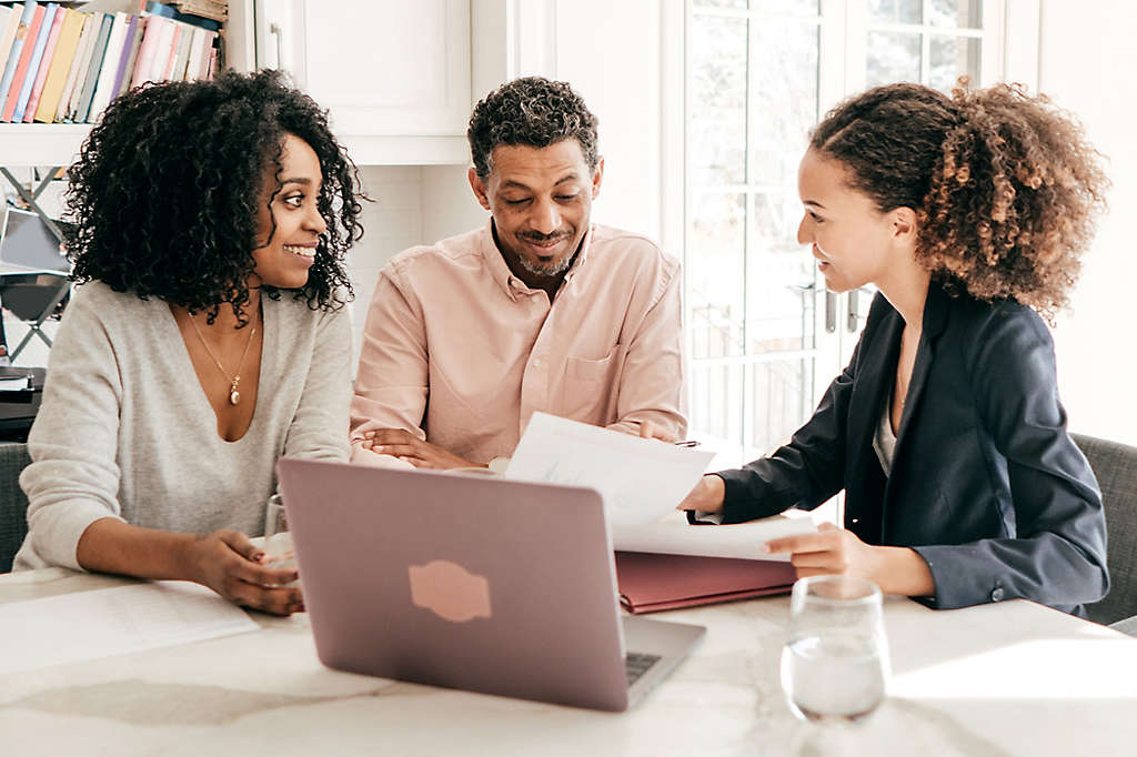 A couple sitting at the kitchen table talking to an agent.