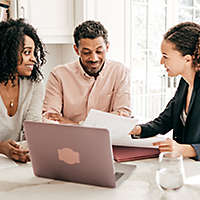 A couple sitting at the kitchen table talking to an agent.