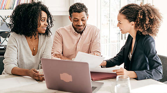 A couple sitting at the kitchen table talking to an agent.