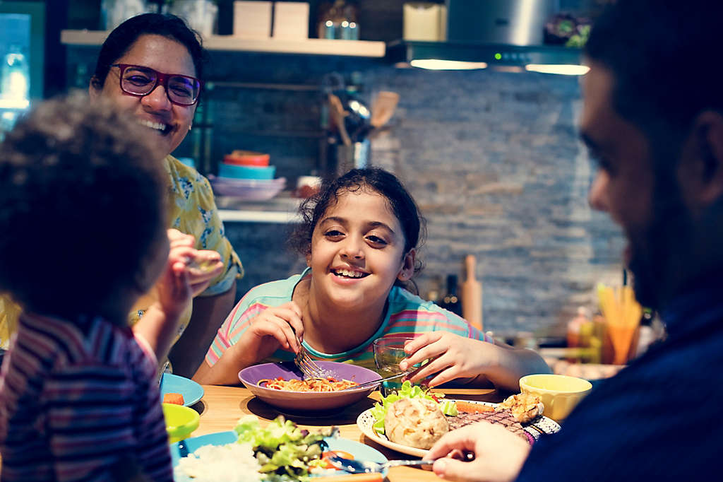 Family eats and laughs around kitchen table