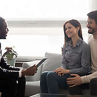 An agent sitting down and talking with a young couple.