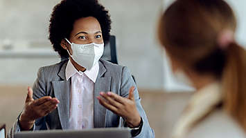 An agent wearing a mask talking with a client.