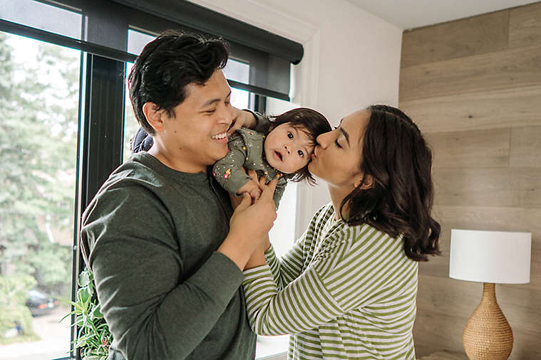 A young couple playing with their baby.