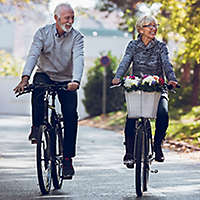 A mature couple riding bikes in the park.