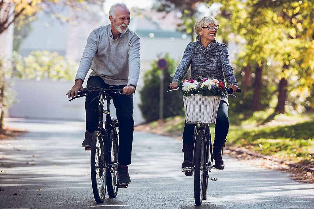 A mature couple riding bikes in the park.