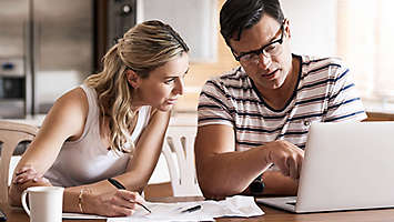 Couple looking at paper work and a computer.