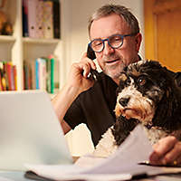 Man on the phone, sitting with his dog.