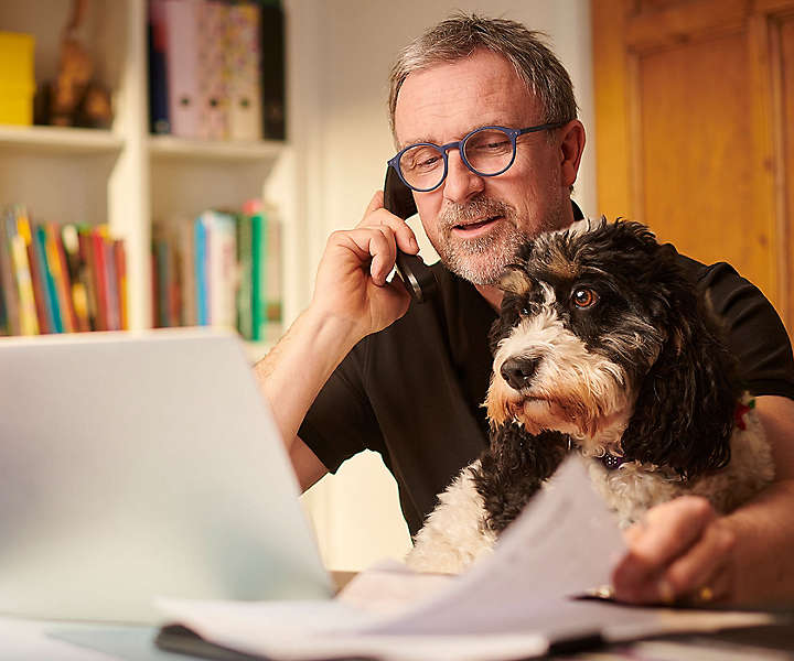 Man sitting with dog looking at the computer