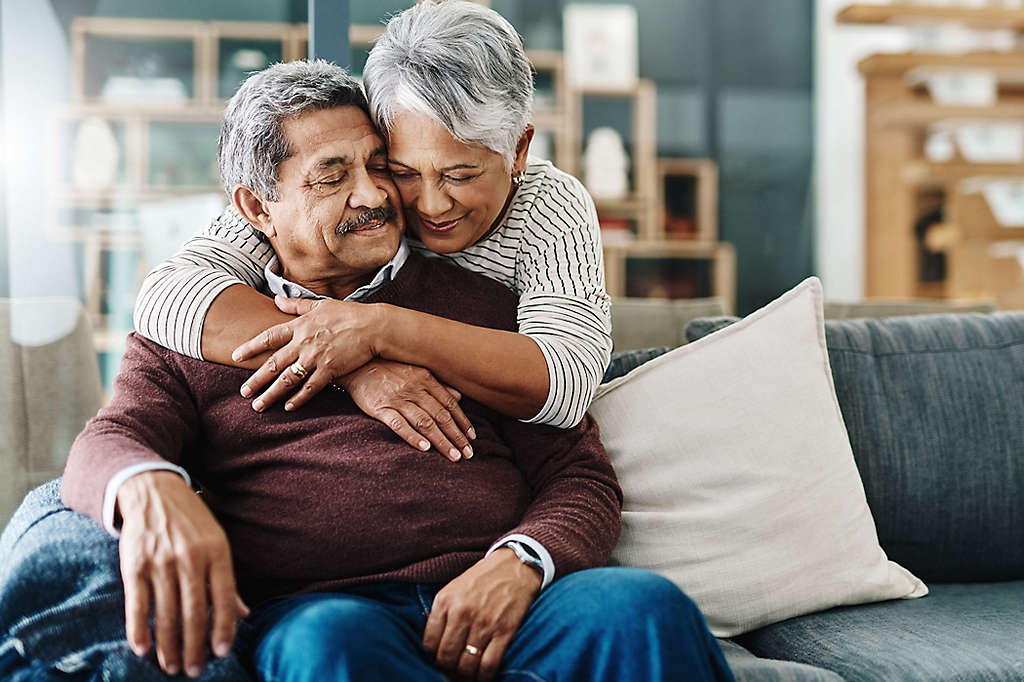 A mature woman hugging her husband from behind.