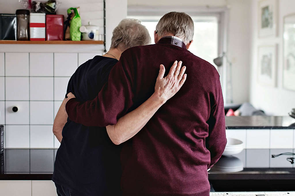 An elderly couple hugging in the home.
