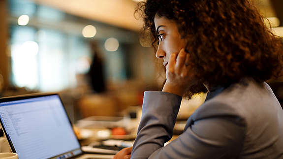 A woman sitting at a desk looking at a spreadsheet on her computer.