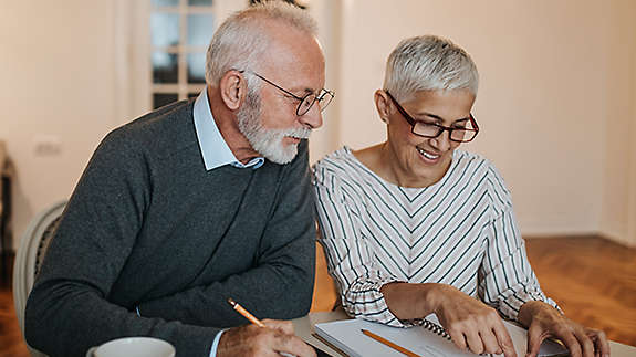 Older couple reviewing their finances at their kitchen table.