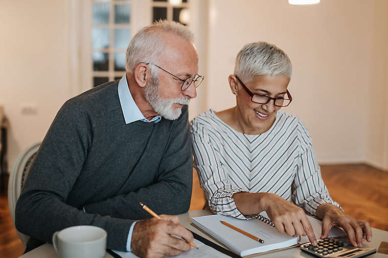 Older couple reviewing their finances at their kitchen table.