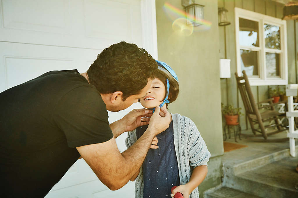 Dad putting on bike helmet on child