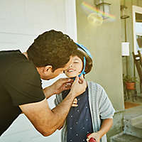 Father helping daughter buckle helmet before riding scooter