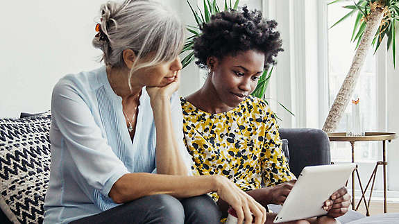 Two women sitting and looking at tablet 