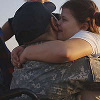 Father in army jacket embracing daughter.