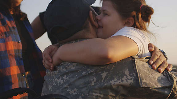 Daughter hugging father in military uniform