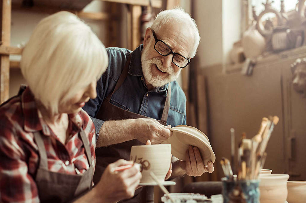 Woman painting pottery with man.