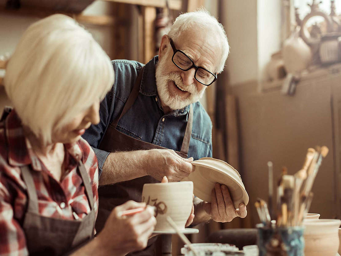 Woman painting pottery with man.
