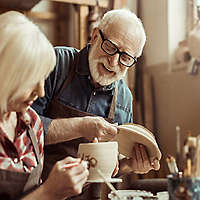 Woman painting pottery with man.