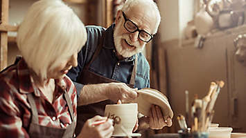 Woman painting pottery with man.