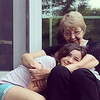 Grandmother holding granddaughter and smiling.