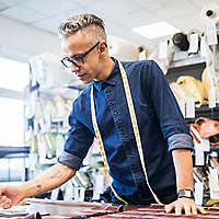 Person working at sewing table with tape measure.